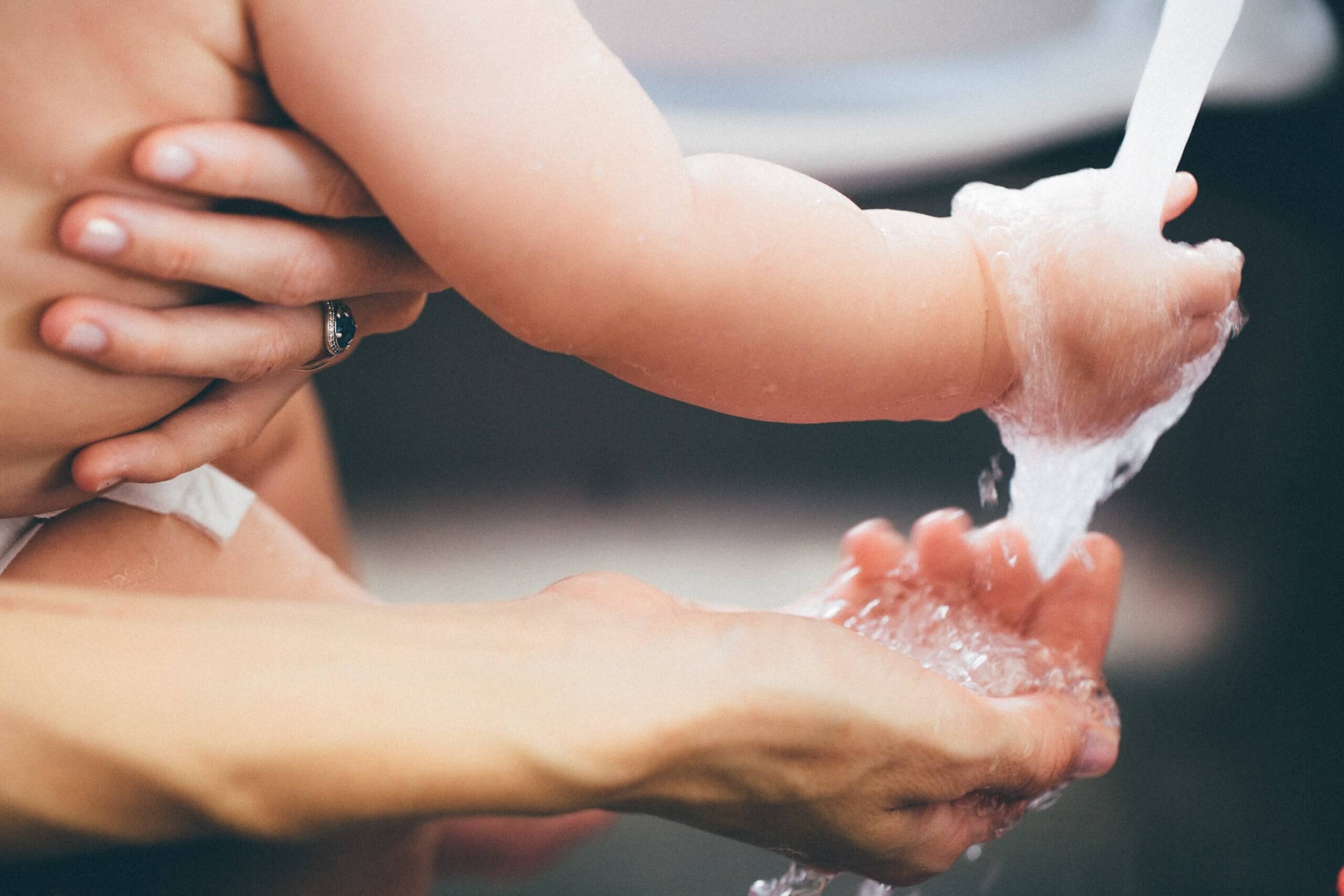 adult and child washing hands at sink